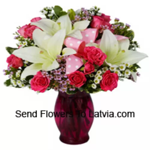 Roses roses et lys blancs avec des remplissages saisonniers dans un vase en verre